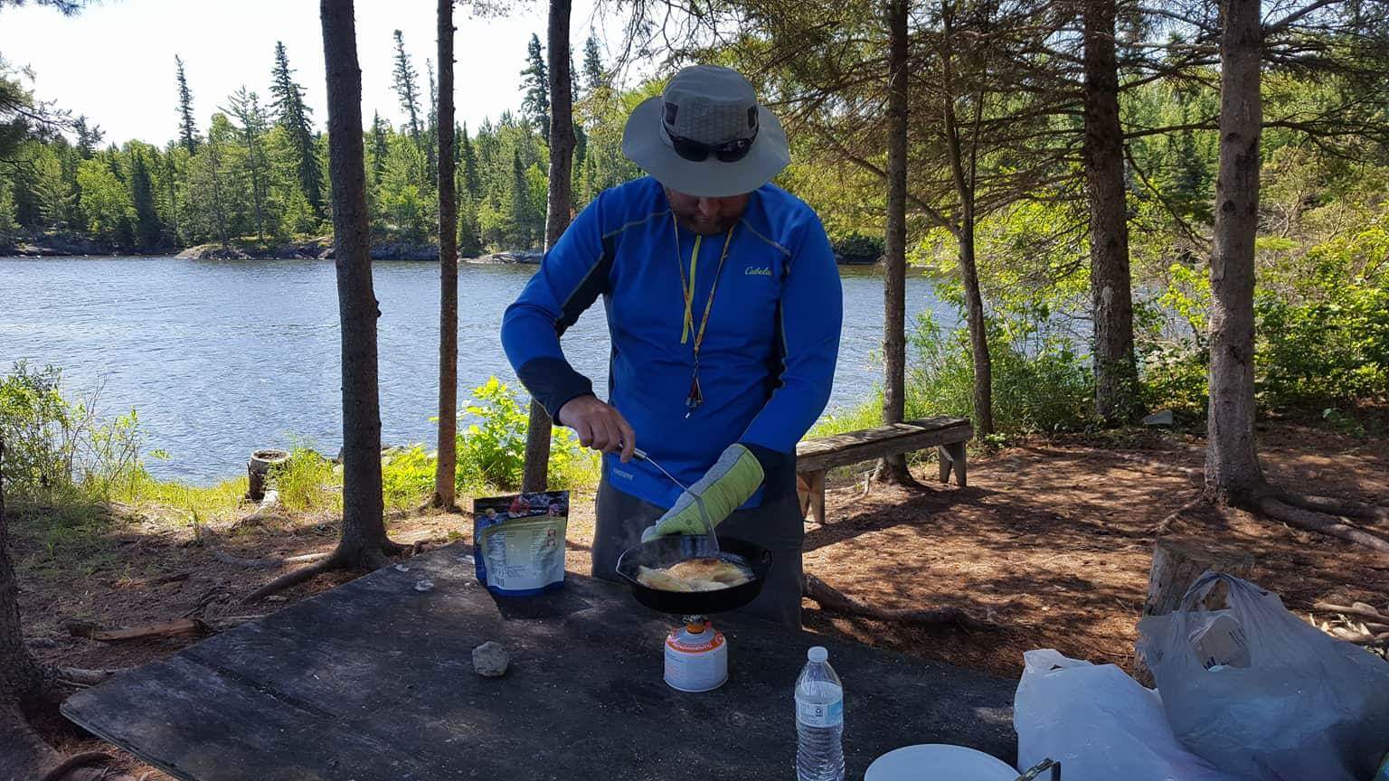 My buddy Jim, cooking up some walleye on a Floating Lodges Houseboat vacation at a shore-lunch site.